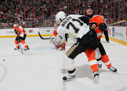 Penguins Evgeni Malkin plays the puck against Scott Hartnell of the Flyers