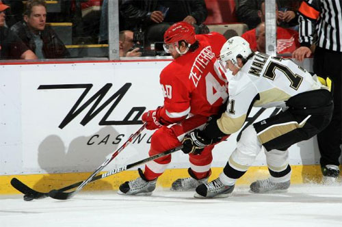 Evgeni Malkin and Henrik Zetterberg fight for the loose puck along the boards